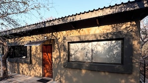 A modern building with a large window, a door, and a small porch area. - Luxury Bush Villa | Private Pool, Hot Tub in Marloth at the Kruger National Park (Marloth Park)