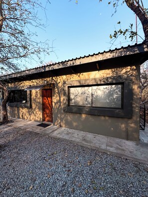 A modern building with a large window, a door, and a small porch area. - Luxury Bush Villa | Private Pool, Hot Tub in Marloth at the Kruger National Park (Marloth Park)