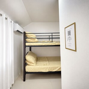 Een slaapkamer met stapelbed en een QR-code in een lijst op de muur.