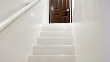 Eine weiße Treppe führt zu einer braunen Tür.