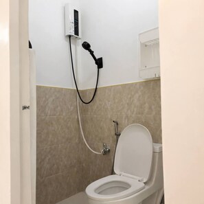 Een badkamer met een toilet, een douche en een wandcontactdoos.