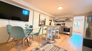 A modern kitchen with a dining area, a flat-screen TV, and a refrigerator. - Elegant Trinity Bellwoods 1BR2BA Parkside Retreat (Toronto)