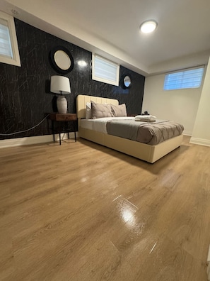 A bedroom with a bed, a nightstand, a lamp, and a wall-mounted mirror. - Elegant Trinity Bellwoods 1BR2BA Parkside Retreat (Toronto)