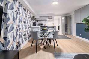 A modern kitchen with a central island, stainless steel appliances, and a dining area with a glass table and chairs.
