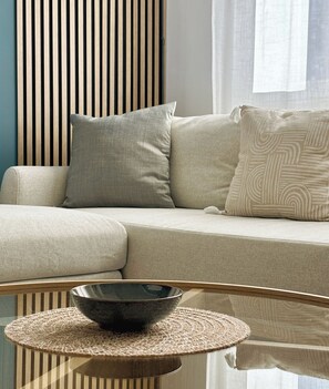 Ein modernes Wohnzimmer mit einer Couch, Kissen und einem Glastisch mit einer Schüssel.