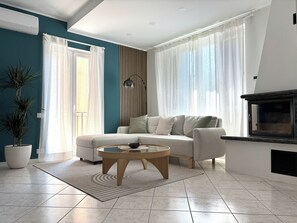 Ein Wohnzimmer mit einer Couch, einem Couchtisch, einem Kamin und einem Blumentopf.