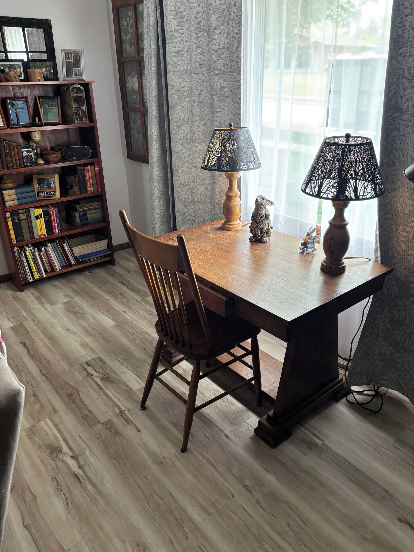 Une table à manger avec des chaises, une lampe et une bibliothèque contenant divers objets.
