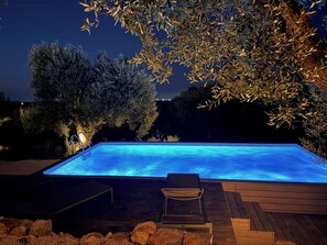 Ein Schwimmbecken mit Holzterrasse und Liegestuhl.