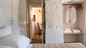 A room with a bed, a small table, and a hanging light fixture. - Stunning Trulli with a Pool, Ocean View, Garden, Relaxation, and Privacy in Monopoli (Puglia)