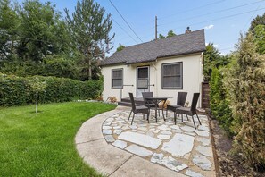 Einbungalow mit einer Steinterrasse und Sitzgelegenheiten im Freien.