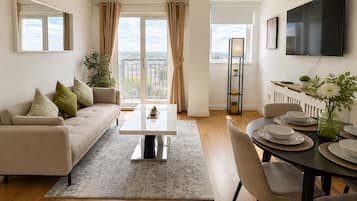 Ein modernes Wohnzimmer mit einer Couch, einem Couchtisch und einem Essbereich mit Tisch für vier Personen.