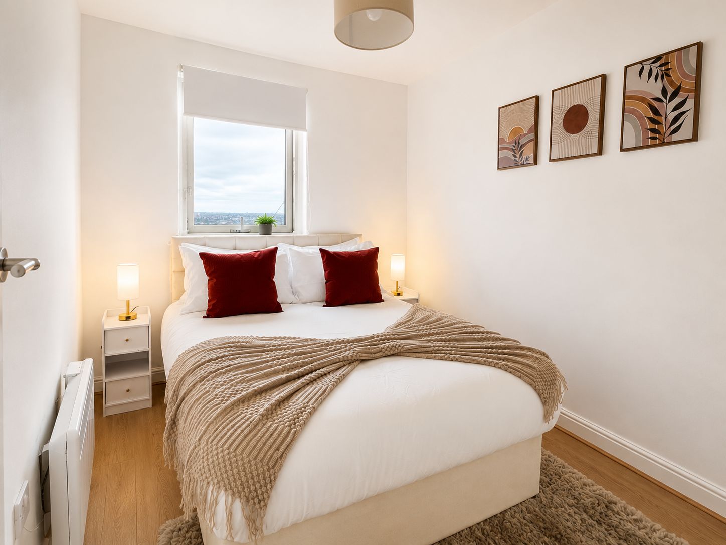 A bedroom with a bed, bedside tables, a window, and wall art.
