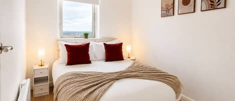Un dormitorio con cama, mesitas de noche, una ventana y decoración en la pared.