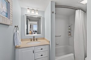 A modern bathroom with a sink, mirror, and shower. - New / Beachfront Condo/ Pool/ Surfing/ EW 801 (Virginia Beach)
