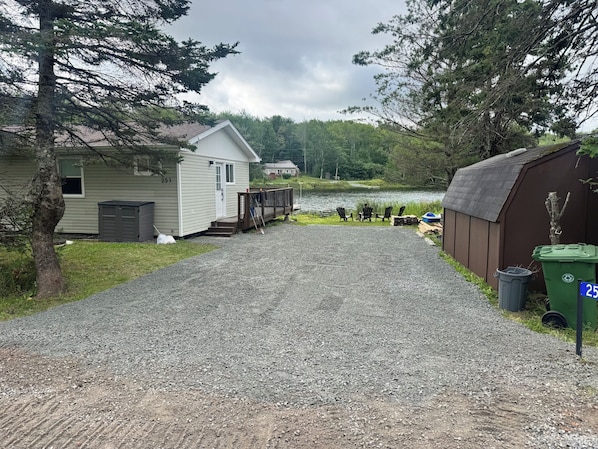 A gravel driveway leading to a cabin with a dock extending into a lake.