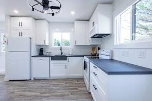 A modern kitchen with white cabinetry, a built-in oven, and a large window providing natural light.