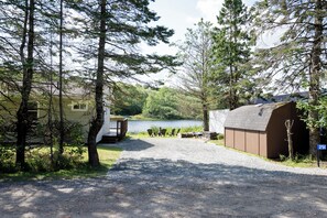 A campground with a gravel path leading to a dock over a lake, surrounded by trees and a cabin. - Lakefront 2-bedroom cottage in beautiful Shortts Lake with AC (Brookfield)