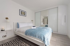 Une chambre à coucher moderne avec un lit, des lampes de chevet, une table de chevet, un miroir et une armoire.