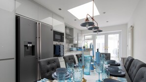 A modern kitchen with a dining area, featuring a built-in oven, microwave, and a large window providing natural light. - Blue Becontree in Goresbrook Village, London (Dagenham)