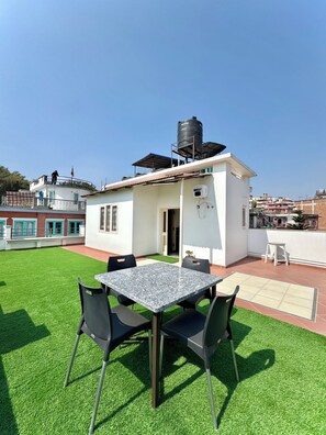 A rooftop terrace with a table and chairs, a water tank, and a view of the surrounding buildings. - Pulukisi Residence (Kathmandu)