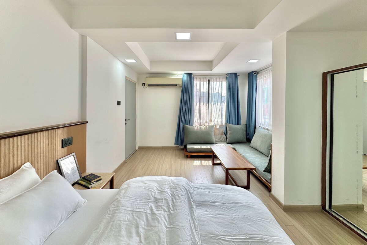 Una habitación de hotel con cama, sofá, una mesita y un espejo.