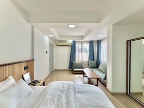A hotel room with a bed, a sofa, a small table, and a mirror. - Pulukisi Residence (Kathmandu)