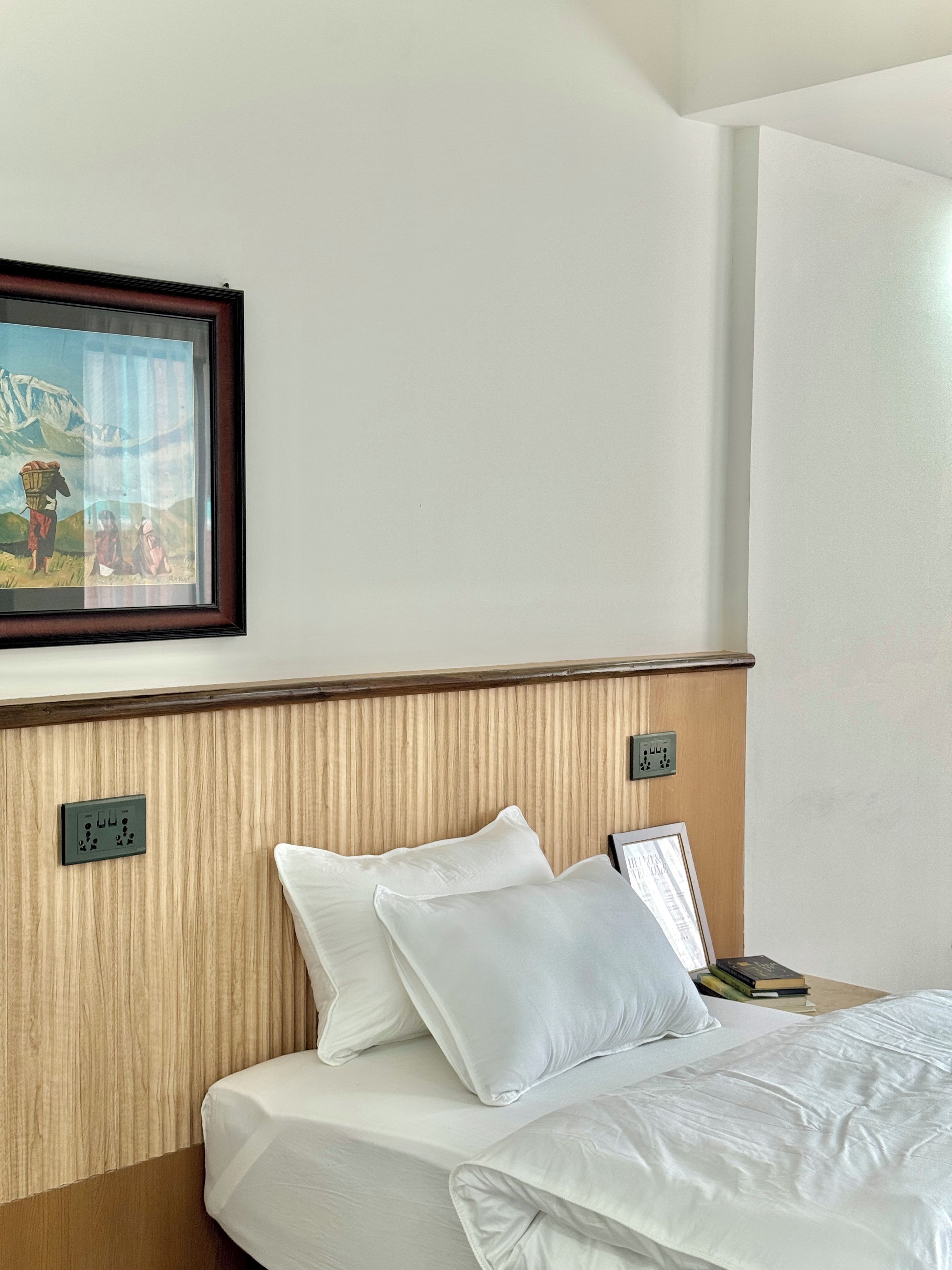 Una habitación de hotel con una cama, almohadas, un cuadro enmarcado en la pared y un cabecero de madera.