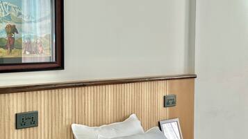 Una habitación de hotel con una cama, almohadas, un cuadro enmarcado en la pared y un cabecero de madera.
