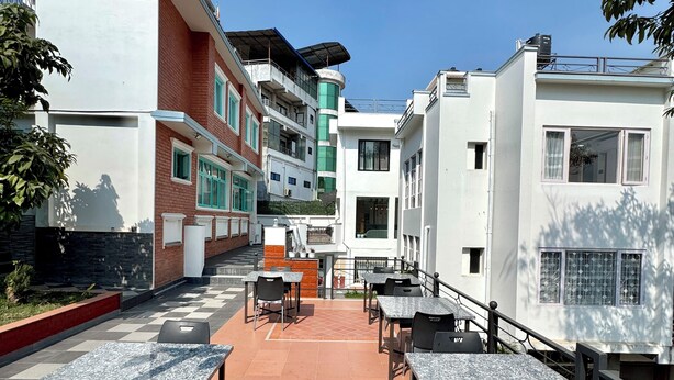 A terrace with outdoor seating and a view of multi-story buildings. - Pulukisi Residence (Kathmandu)