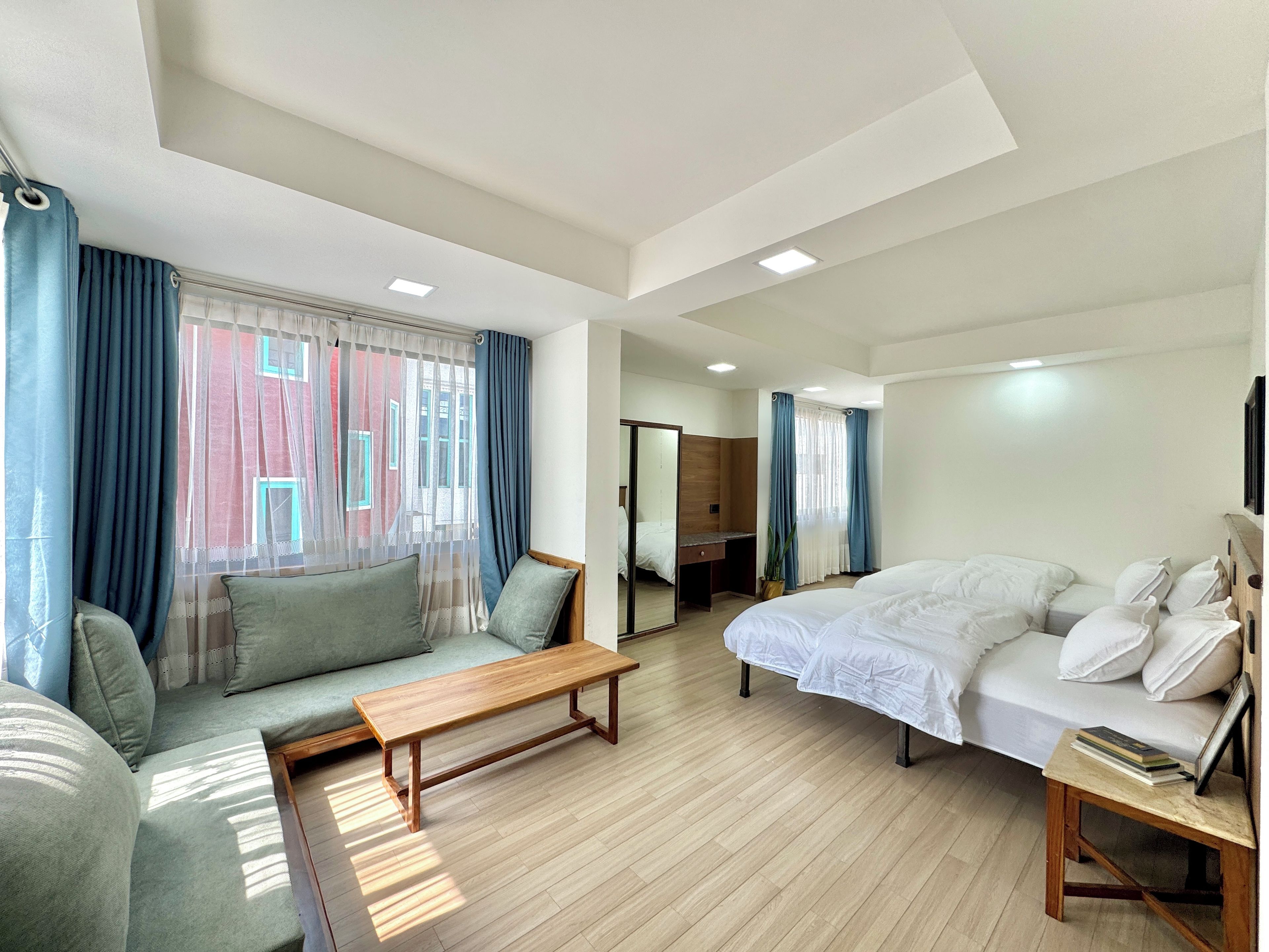 A modern hotel room with a sofa, a bed, a wooden bench, and a small table with books.