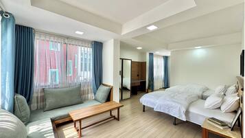 A modern hotel room with a sofa, a bed, a wooden bench, and a small table with books.