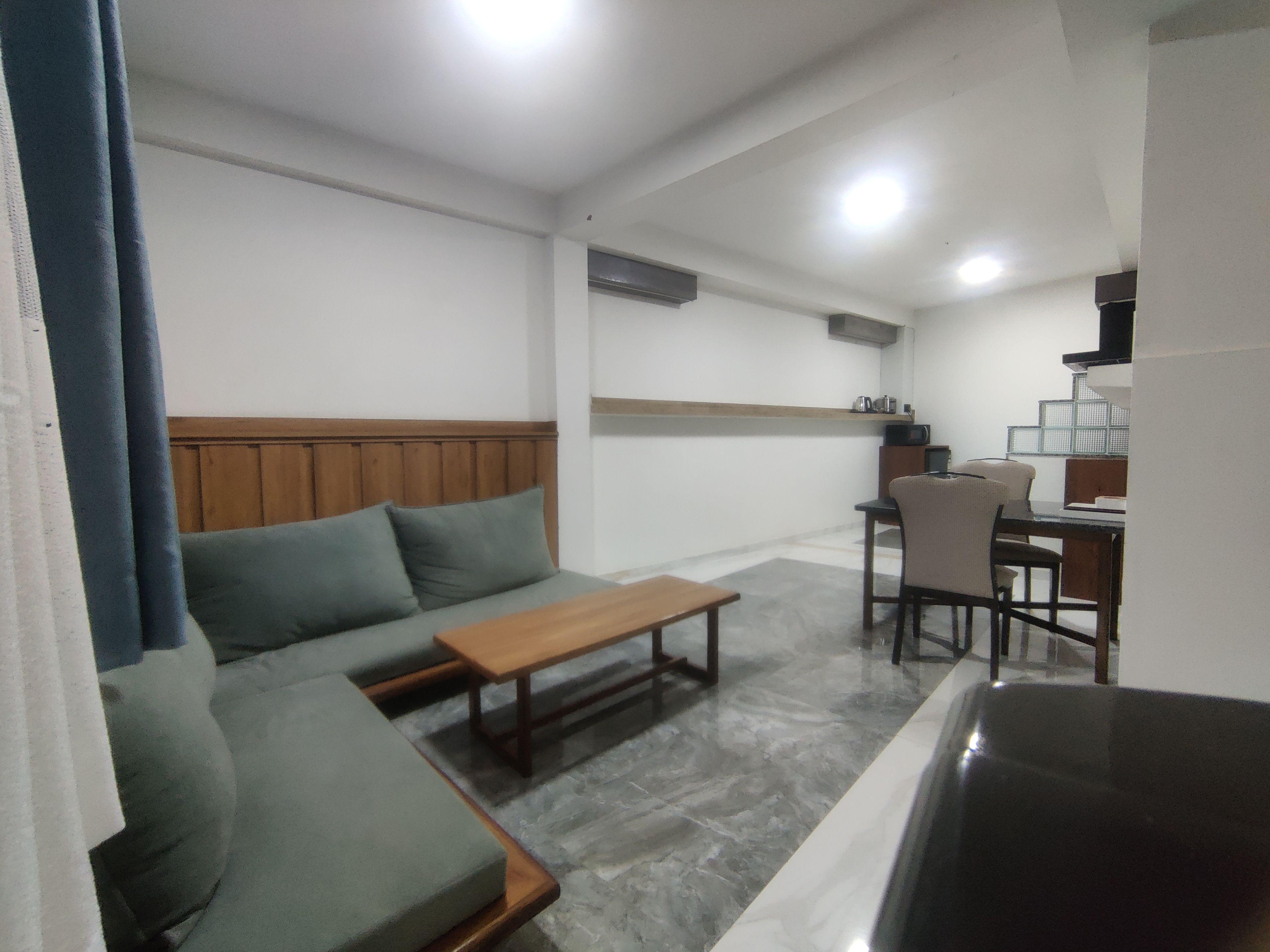 A living area with a sofa, a wooden coffee table, and a dining table with chairs.