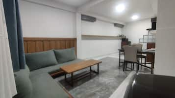 A living area with a sofa, a wooden coffee table, and a dining table with chairs.