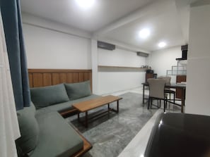 Un espacio de sala con un sofá, una mesa de centro de madera y una mesa de comedor con sillas.