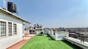 A rooftop terrace with artificial grass, a table, and chairs. - Pulukisi Residence (Kathmandu)