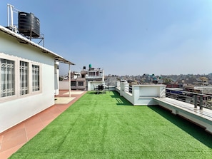A rooftop terrace with artificial grass, a table, and chairs. - Pulukisi Residence (Kathmandu)