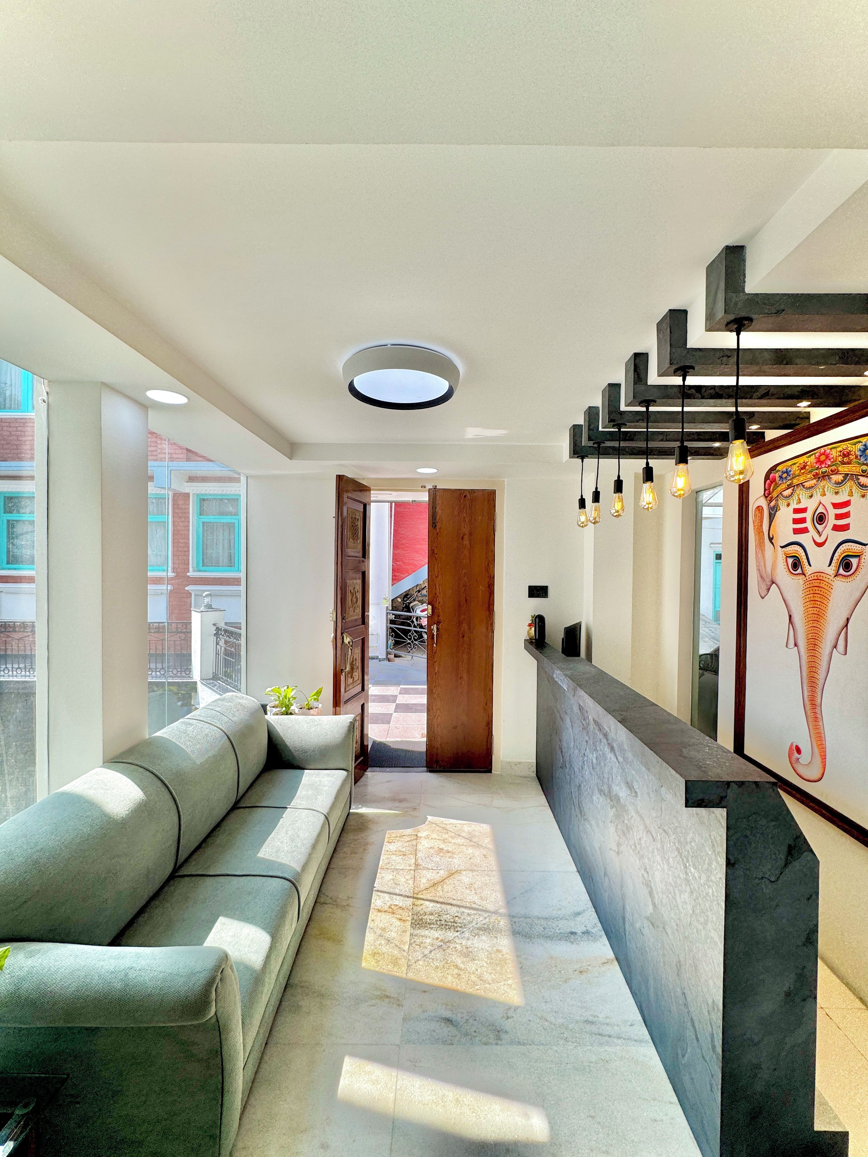 A modern interior with a sofa, a reception desk, and a view of the outside.