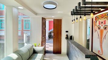 A modern interior with a sofa, a reception desk, and a view of the outside.