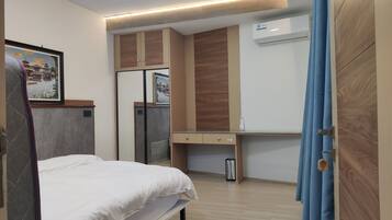 Ein Schlafzimmer mit Bett, Kleiderschrank, Schreibtisch und Klimaanlage.