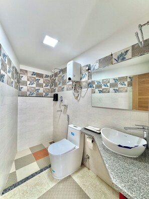 A bathroom with a toilet, bidet, and sink, featuring patterned tiles and a mirror. - Pulukisi Residence (Kathmandu)