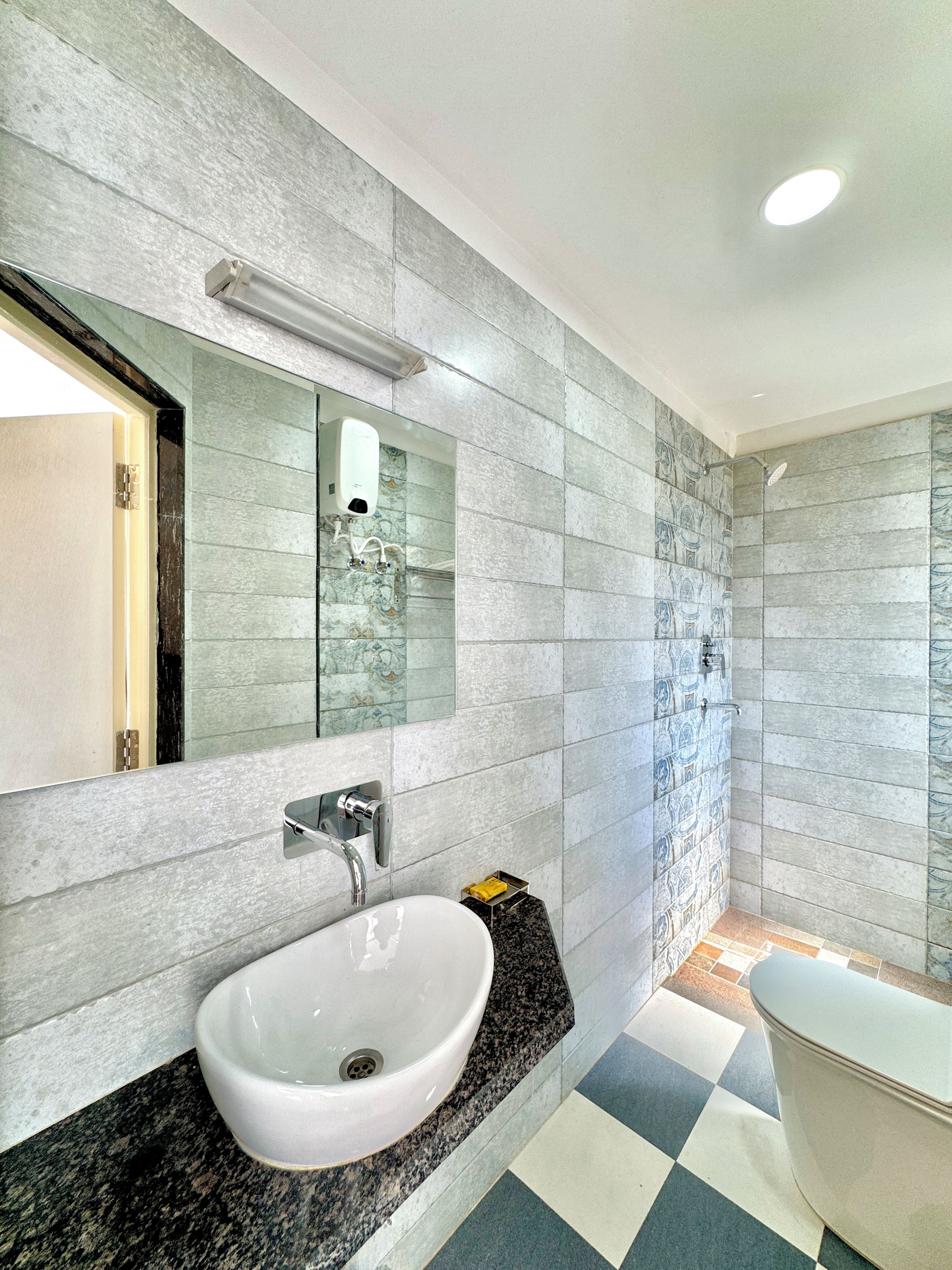 A modern bathroom with a white sink, a mirror, and a shower area.