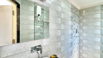 A modern bathroom with a white sink, a mirror, and a shower area.