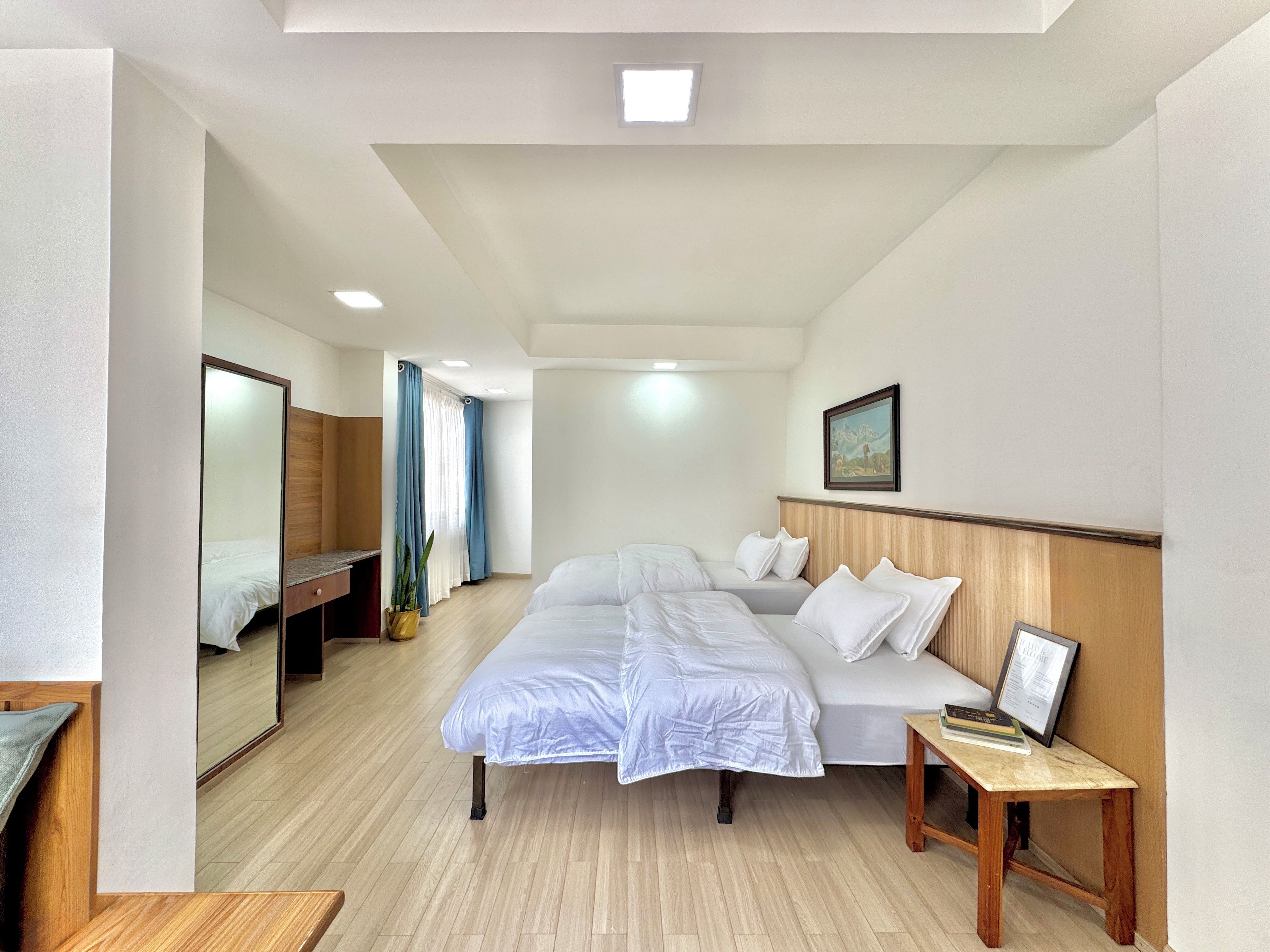 A hotel room with a large bed, a bedside table, a mirror, and a painting on the wall.