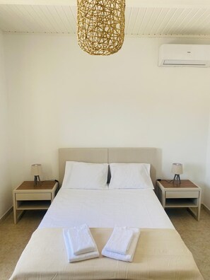 A hotel room with a bed, two bedside tables, a hanging light fixture, and an air conditioning unit. - A romantic getaway with a pool in the heart of the Algarve. For adults only. (Silves)