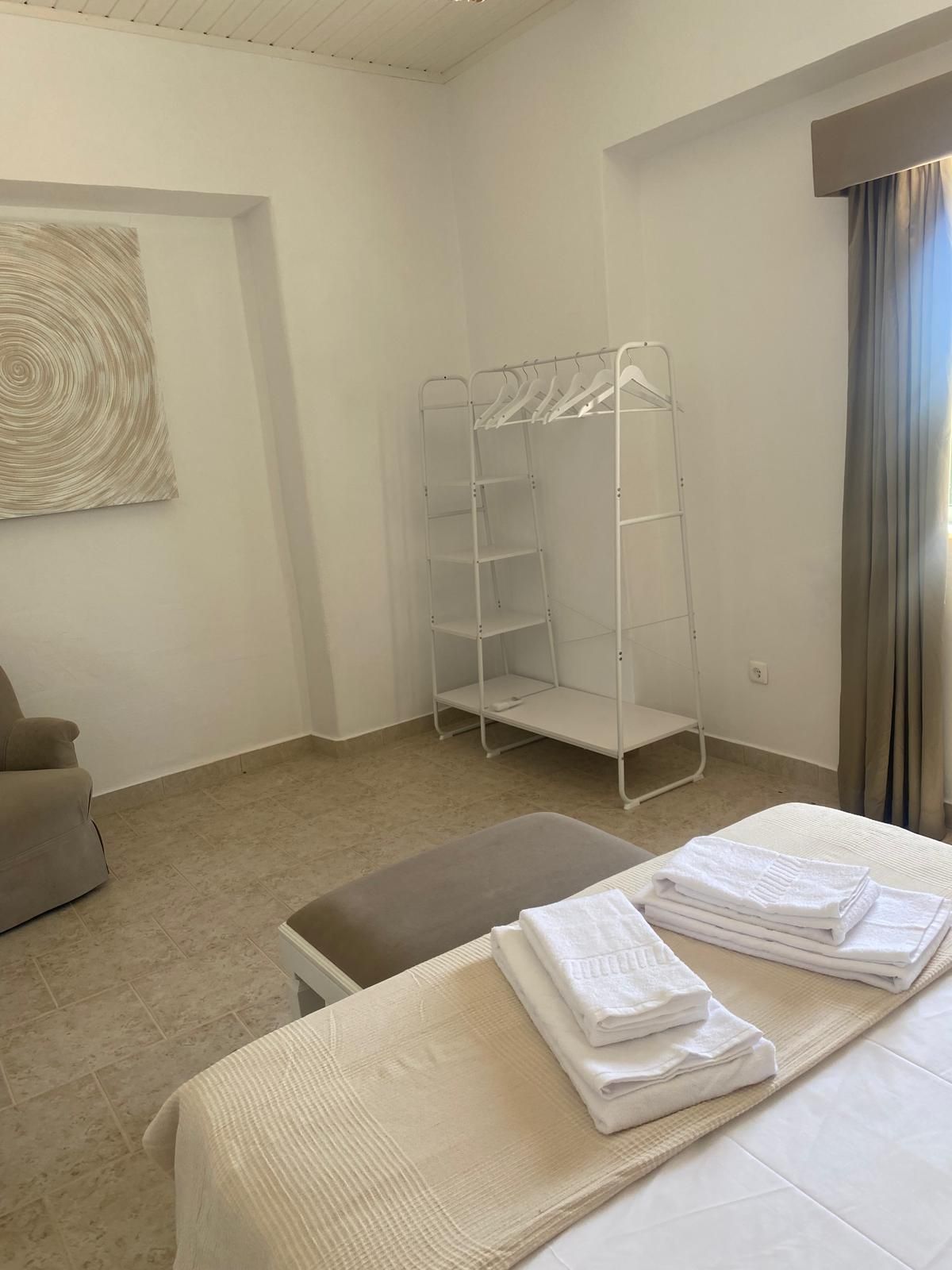 Hotellihuone, jossa on sänky, oleskelualue, vaatekaappi ja taulu seinällä.