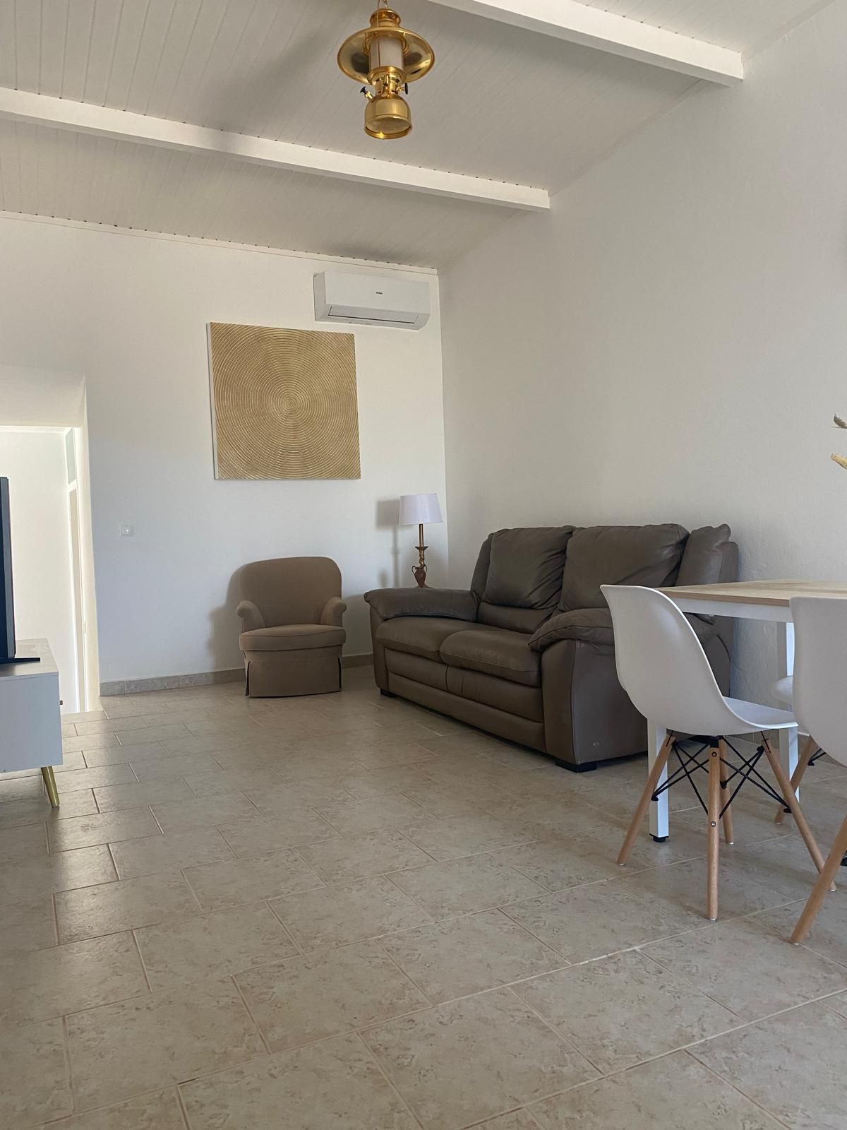 A living room with a sofa, a small armchair, a coffee table, and a lamp.