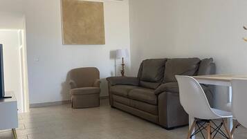 A living room with a sofa, a small armchair, a coffee table, and a lamp.