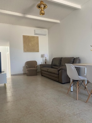 A living room with a sofa, a small armchair, a coffee table, and a lamp. - A romantic getaway with a pool in the heart of the Algarve. For adults only. (Silves)
