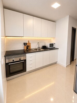 A modern kitchen with white cabinets, a black countertop, a built-in oven, a microwave, and a sink. - A romantic getaway with a pool in the heart of the Algarve. For adults only. (Silves)