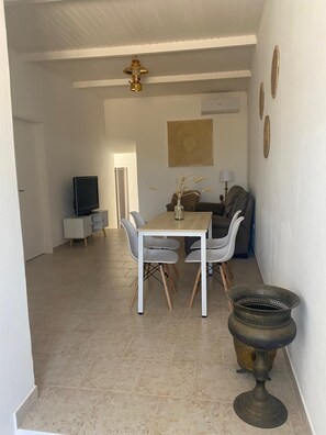 A dining area with a table and chairs, a television in the background, and a decorative vase on the table. - A romantic getaway with a pool in the heart of the Algarve. For adults only. (Silves)